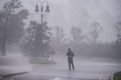 A reporter covers his face as he reports while Hurricane Delta makes landfall in Lake Charles, Louisiana. AFP