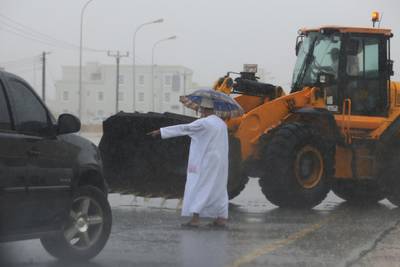 An Omani official gestures to a loader driver to tear away a road divider. Kamran Jebreili / AP Photo