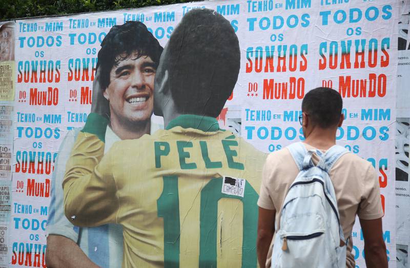 A man looks at a collage on a wall depicting Pele and Maradona, in Sao Paulo, Brazil. Reuters