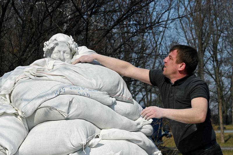 City workers cover the monument to Italian poet, writer and philosopher Dante Alighieri with sandbags to protect against Russian shelling in Kyiv. AFP