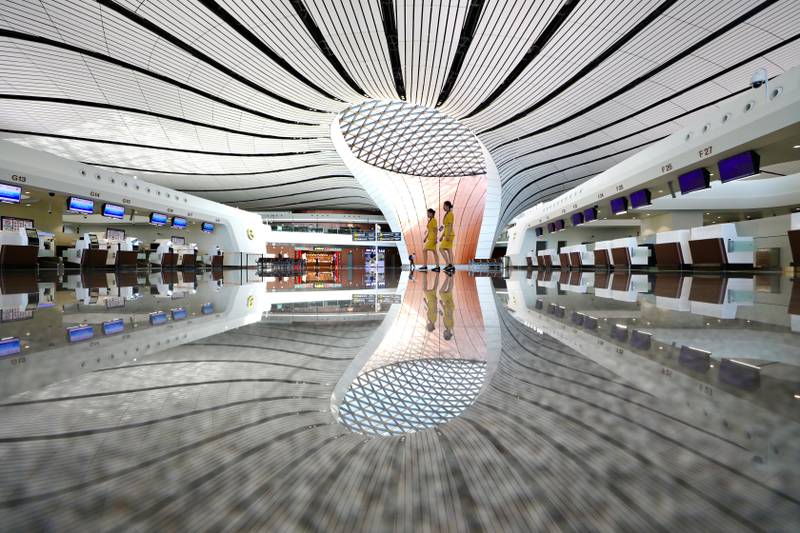 Staff members walk past a terminal hall of the newly opened Daxing International Airport in Beijing, China September 25, 2019. REUTERS/Stringer ATTENTION EDITORS - THIS IMAGE WAS PROVIDED BY A THIRD PARTY. CHINA OUT.