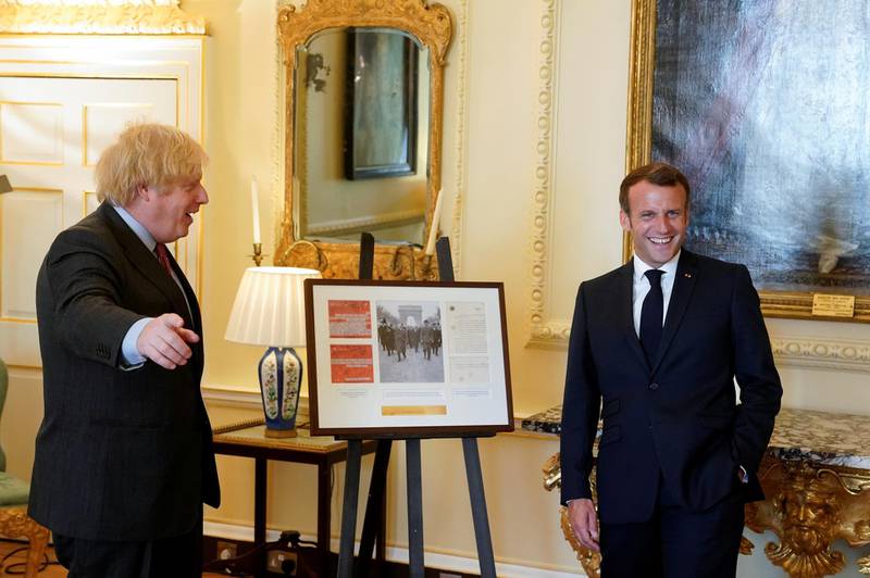 British Prime Minister Boris Johnson and French President Emmanuel Macron pose as they look at documents and artifacts related to former French President Charles de Gaulle during a visit at Downing Street in London. Reuters
