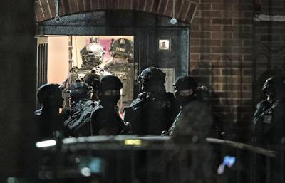 Armed police officers investigate at a block of flats off the Basingstoke Road in Reading after an incident at Forbury Gardens park in the town centre of Reading, England. PA via AP