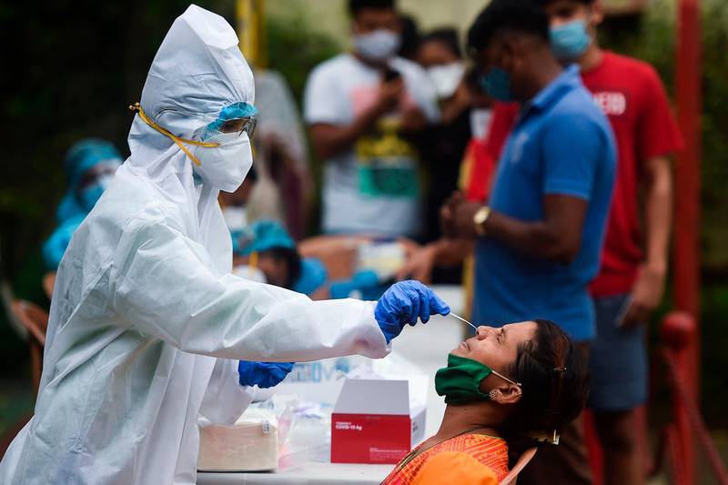 A medical staff wearing Personal Protective Equipment (PPE) takes a nasal swab sample from a resident for a Covid-19 Coronavirus test, in a residential area in Mumbai, on September 14, 2020. / AFP / Punit PARANJPE                      
