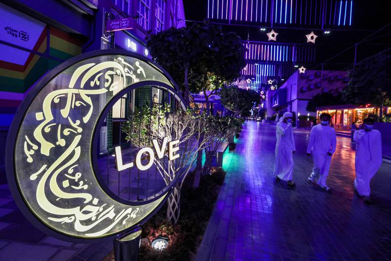 Emirati youths walk past a large lit decoration in the shape of a crescent moon bearing calligraphic text in Arabic reading "Ramadan Mubarak", at the City Walk district of Dubai at the start of the first night of the Muslim holy fasting month of Ramadan. AFP