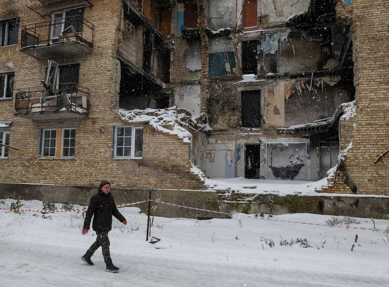 Resident Tetiana Reznychenko walks past a work by world-renowned graffiti artist Banksy, on the wall of a destroyed building in the Ukrainian village of Horenka. Reuters