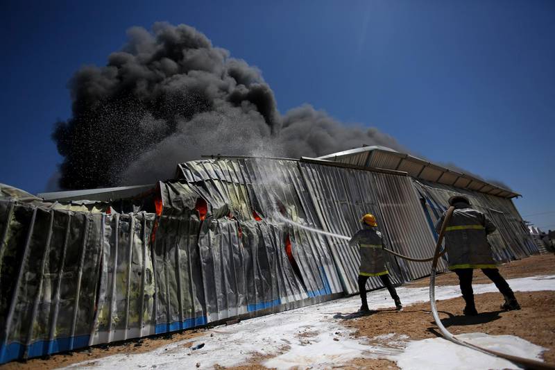 Palestinian firefighters work to extinguish a fire at a paint factory after it was hit by an Israeli air strike in Rafah, Gaza Strip. AP Photo