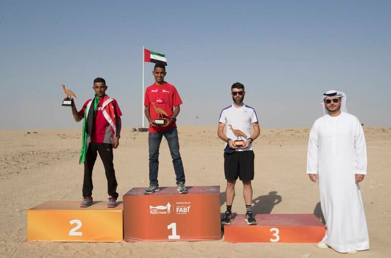 Winners of the 50km men's race: Rachid El Morabity in first place, Salameh Al Aqra in second, and Gareth Gallagher in third, with Mustafa Al Khalfawi, head of global banking UAE at FAB.