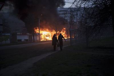 A couple of residents walk past burning shops after a Russian attack in Kharkiv, Ukraine. AP Photo