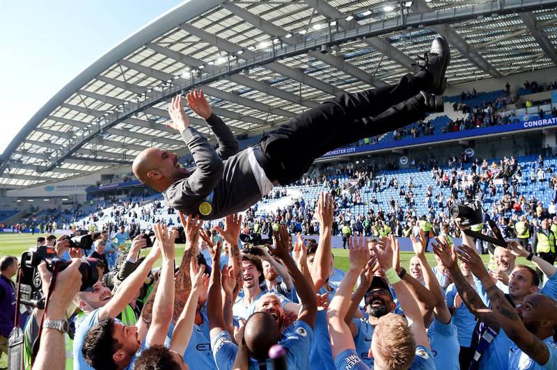 Manchester City players throw manager Pep Guardiola in the air as they celebrate winning the Premier League title. Getty Images