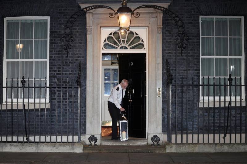 In a more peaceful scene in Downing St, a doorman lays a candle lit by Prime Minister Boris Johnson as a tribute to Sarah Everard. Reuters