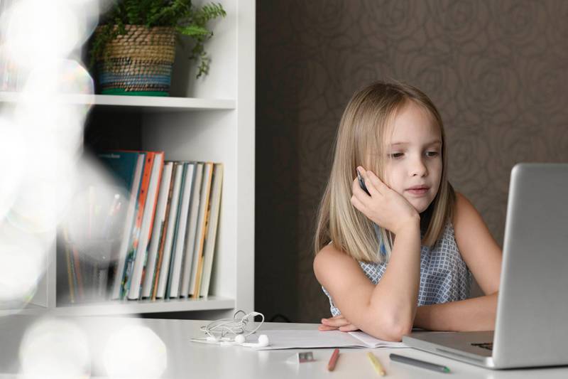 Girl sitting at table at home using laptop. Getty Images