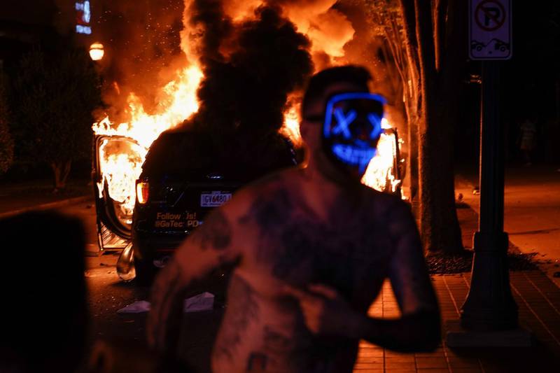 A masked protester runs in front of a burning police car in Atlanta, Georgia. Getty Images/AFP