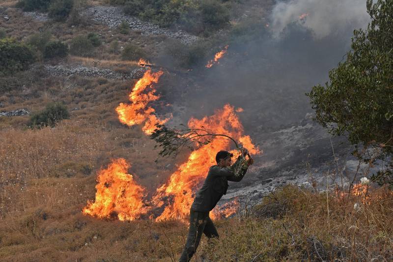 A handout picture released by the official Syrian Arab News Agency (SANA) shows a Syrian man attempting to put off a fire on a hill in Ain Halaqim, in the western countryside of Syria's Hama governorate.  AFP