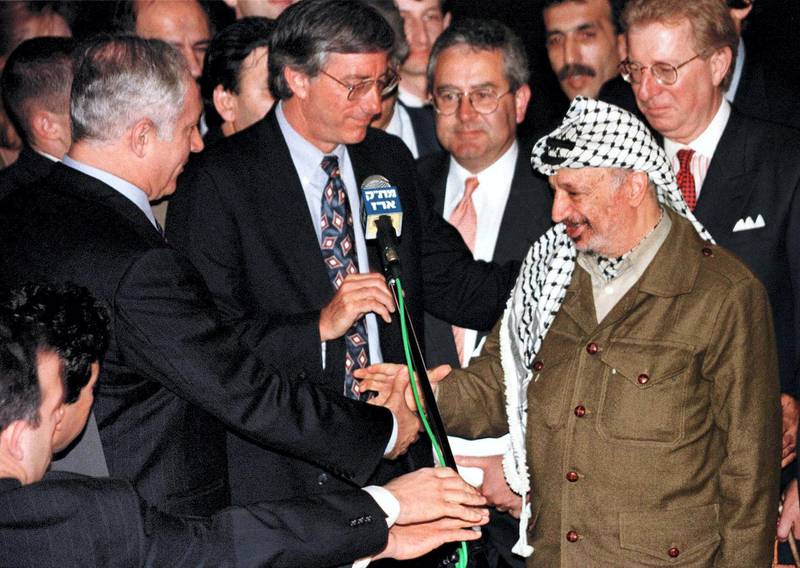 Palestinian President Yasser Arafat (R) shakes hands with Israeli Prime Minister Benjamin Netanyahu after United States' special envoy Dennis Ross (C) spoke, early January 15 after the two leaders met and agreed on the term for the long overdue Israeli troop redeployment in Hebron. The talks lasted less than two hours and concluded months of negotiations which will lead to the end of the Israeli military occupation in about 80 percent of Hebron.

MIDEAST