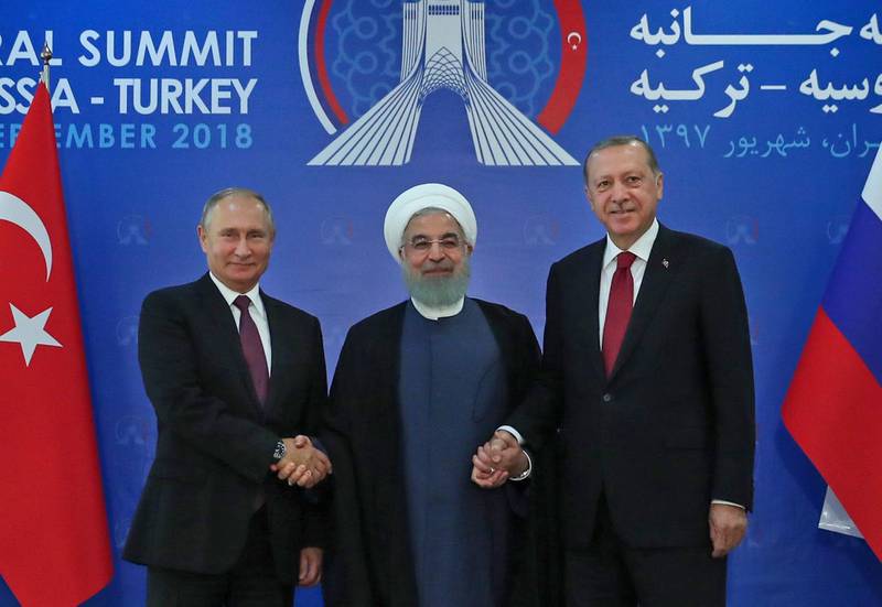 A handout picture provided by the office of Iranian President Hassan Rouhani (C) shows him holding hands with Turkish President Recep Tayyip Erodgan (R) and Russian President Vladimir Putin (L) in Tehran on September 7, 2018, as Iran hosted a summit on the Syrian conflict. (Photo by HO / Iranian Presidency / AFP) / RESTRICTED TO EDITORIAL USE - MANDATORY CREDIT "AFP PHOTO / Iranian President's Office" - NO MARKETING NO ADVERTISING CAMPAIGNS - DISTRIBUTED AS A SERVICE TO CLIENTS