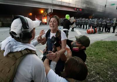 Protesters help a woman who was hit in the throat with a rubber bullet during a demonstration next to the city of Miami Police Department downtown in Miami. AP Photo