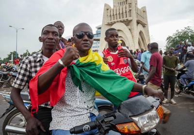 A man wears a national flag as he celebrates with others in the streets in the capital Bamako, Mali. AP Photo