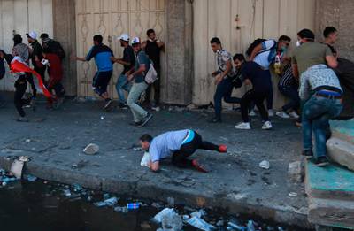 Anti-government protesters run for cover while security forces fire live ammunition in the air to disperse protesters, during ongoing protests, in Khilani Square, Iraq. AP Photo