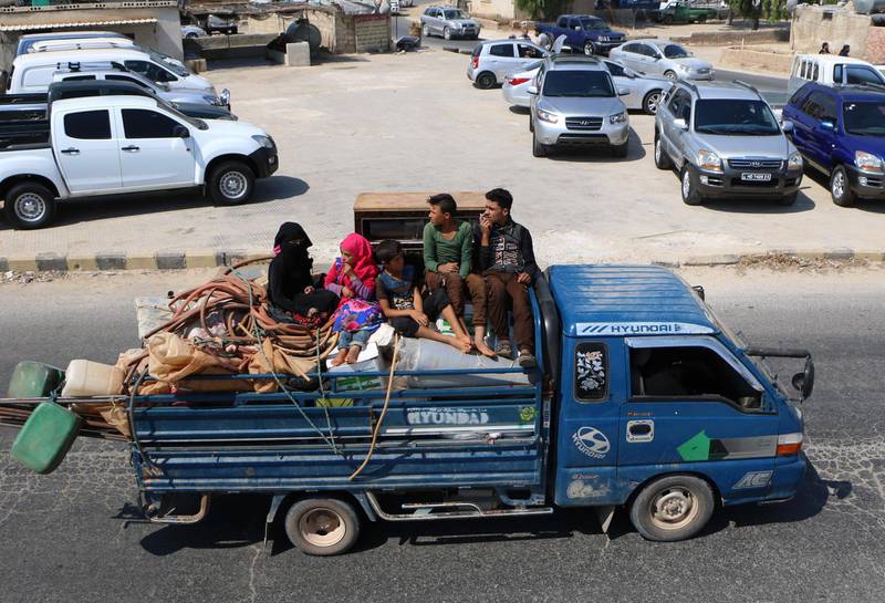 Displaced Syrians who fled from regime raids ride in a truck with their belongings arrive near a camp in Kafr Lusin near the border with Turkey in the northern part of Syria's rebel-held Idlib province.  AFP