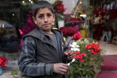 An Afghan boy in Kabul holds a red rose as he looks for money before Valentine's Day. AP