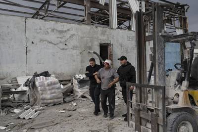 Security guards help an injured man following a Russian bombing of a factory in Kramatorsk. AP