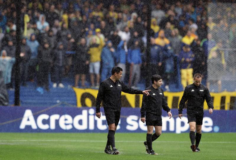 Referee Roberto Tobar along with his team officials, inspects the pitch, before suspending the match. AFP