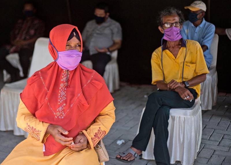 People wear protective masks and sit apart as they wait for the results of their coronavirus antibody tests in North Sumatra, Indonesia. AP