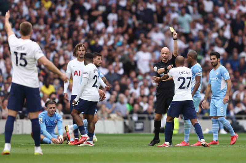 Referee Anthony Taylor shows Lucas Moura a yellow card.