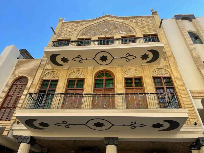 A building's balconies freshly painted with Islamic motifs, on the street.