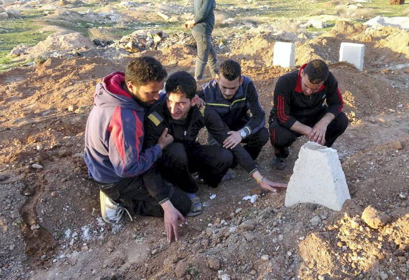 IDLIB, SYRIA - APRIL 6: Abdel Hameed Alyousef (2nd L) mourns over his wife and twin babies, killed in the chemical attack by Assad Regime, at their cemetery in Idlib, Syria on April 6, 2017. Abdel Hameed Alyousef lost his wife and 9 month old twin babies named Aya and Ahmad in addition to 13 of his family members in the chemical attack. The grief-stricken father said: " Dear God took Ahmad and Aya, I am not upset over this. Gulf countries do not deliver an international society which they speak of. We will be patient until the last day and the victory will come. We are not the first nor the last. Our children have been dying in our hands for 6 years. No one seems to help." Assad Regime struck Khan Shaykhun district of Idlib in Syria with a chemical weapon leaving at least 100 civilians, including women and children, dead and at 500 affected from the gas. 

 (Photo by Mohammed Al Daher/Anadolu Agency/Getty Images)