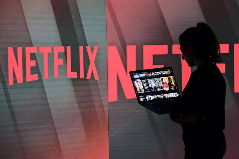A woman browses the Netflix Inc. homepage on a laptop computer amongst illuminated screens bearing the company logo in this arranged photograph in London, U.K., on Tuesday, June 26, 2018. Addressing a room filled with New Delhi’s business elite earlier this year, Netflix Inc. Chief Executive Officer Reed Hastings offered a prediction: His company’s next 100 million customers will come from India. Photographer: Chris Ratcliffe/Bloomberg