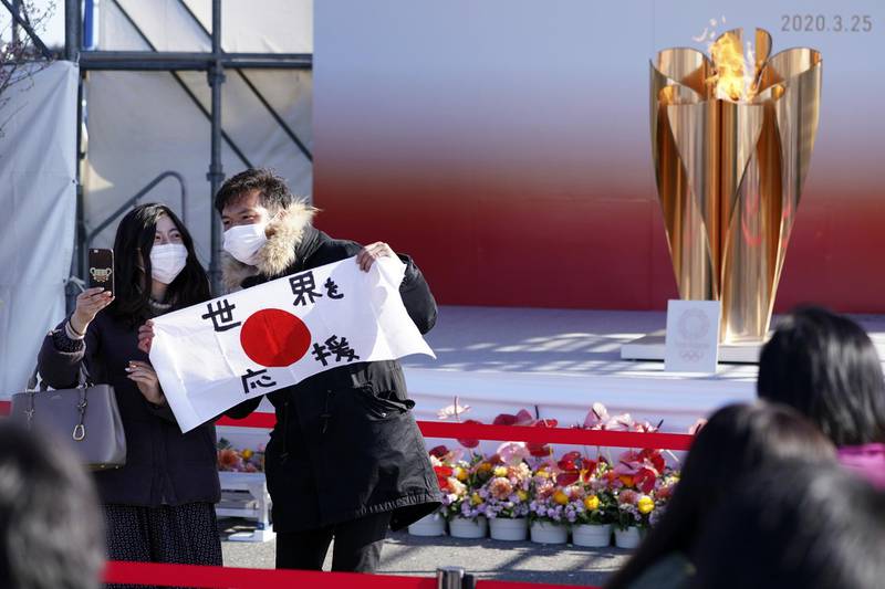 Visitors pose with a national flag reading "Supporting the world" during the Olympic "Flame of Recovery" display ceremony in Iwaki, Fukushima. AP