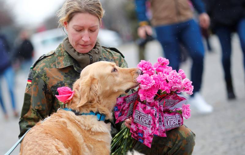 A female soldier of the German Armed Forces pets a dog as she distributes flowers to women during the International Women's Day near the Brandenburg Gate in Berlin, Germany. REUTERS
