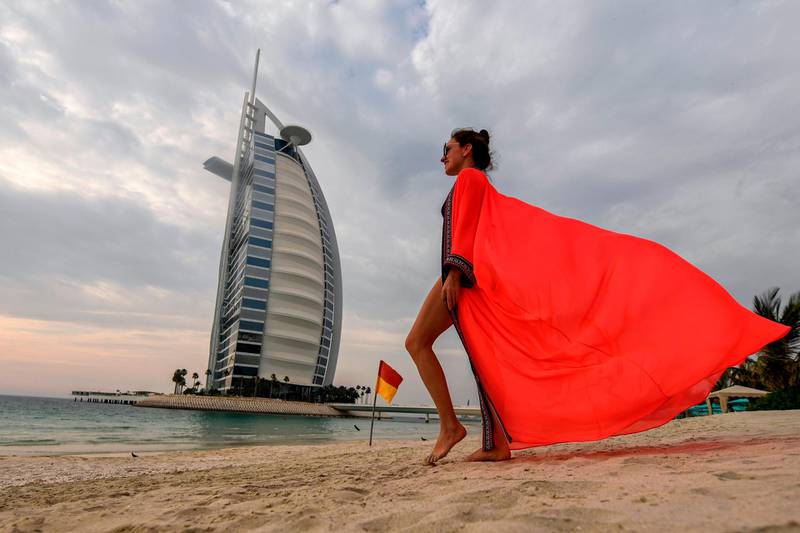 A woman bather walks along the beach shoreline near the Burj Al Arab hotel in Dubai.   AFP