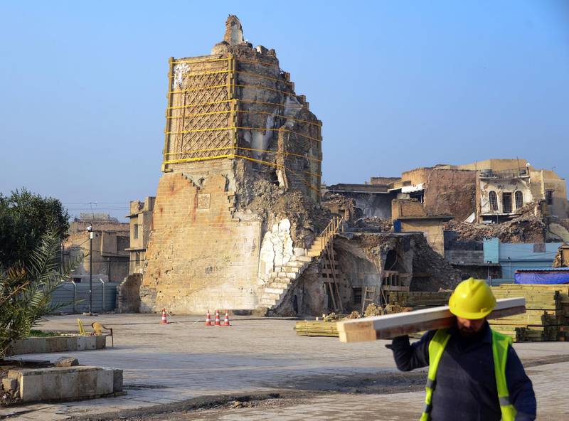 An Iraqi worker carries wood logs during the reconstruction of the "Al-Hadba" leaning minaret in Mosul’s war-ravaged old town.  AFP