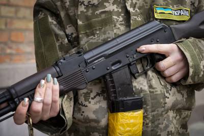 An armed civil defence woman holds a Kalashnikov assault rifle while patrolling an empty street in Kiev. AP