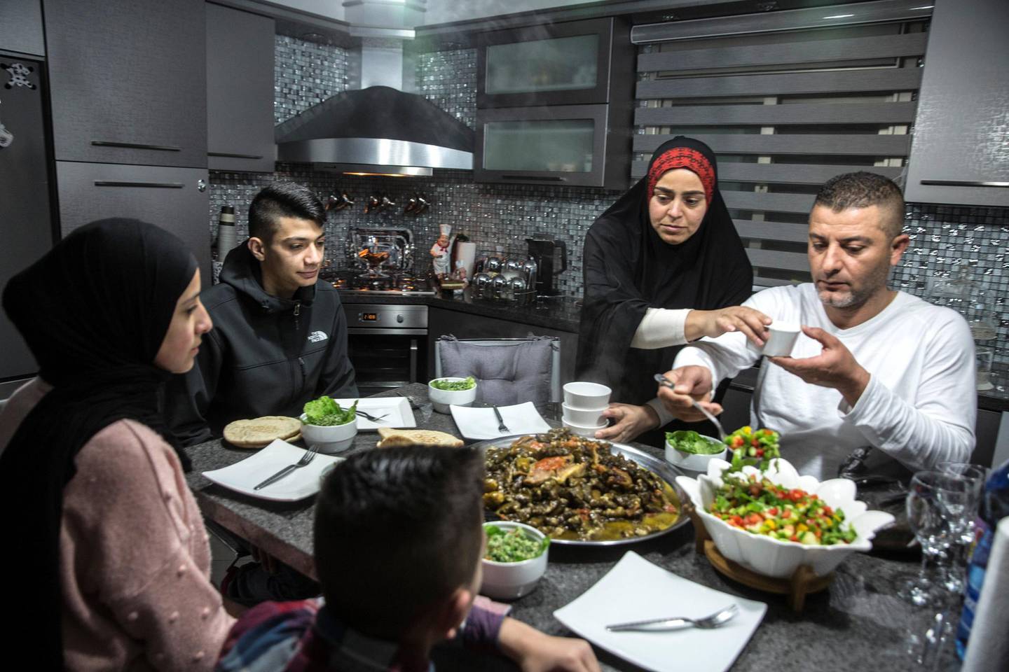 Palestinian Yehiya Derbas (L) with his family during a Saturday afternoon lunch at his home in  Issawiyah, a hardened and impoverished east Jerusalem neighborhood on March 9,2019.The day the Trump administration announced last December that it would be moving the United States Embassy to Jerusalem, Yehiya DerbasÕ life changed forever.  Derbas, then a slight 16-year-old, joined in Palestinian protests against the move. And like many young men before and after him, Derbas told The National that Israeli forces shot him and later imprisoned him for one year on charges related to the dayÕs violence.  

Upon his release in early February, now marked as an ex-con, Derbas returned to a city that in most ways has remained the same day-to-day Ñ but that intangibly has significantly changed. (Photo by Heidi Levine For The National).
