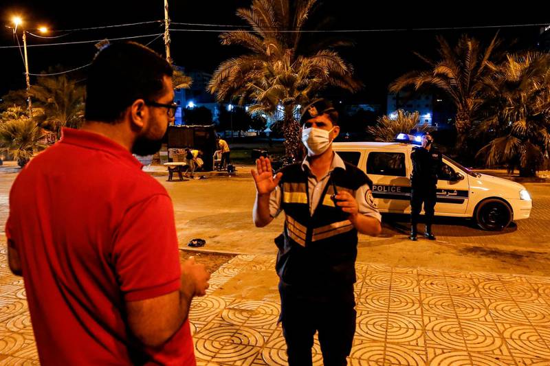 A Palestinian security officer speaks to a man following an appeal for shutting down public spaces across the Gaza City amid the rising number of coronavirus cases.  AFP