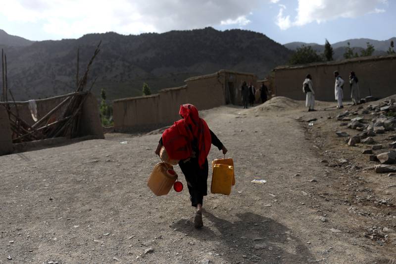 An Afghan girl carries empty water containers in Gayan village after the quake. Reuters