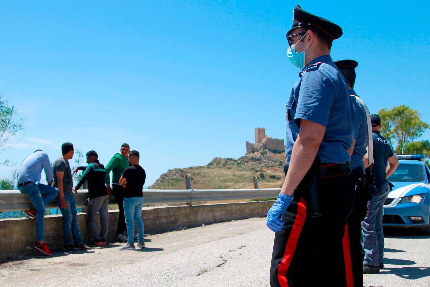 Italian police detain and check immigrants found along the road and in the countryside in Palma di Montechiaro near Agrigento Sicily on May 24, 2020.  About 400 migrants were landed on May 24, 2020, on a beach in Sicily from a boat which slipped away, this is the largest migrant arrival in Sicily for several years but smaller groups, mostly from Libya, are frequent arrivals. / AFP / Sandro CATANESE
