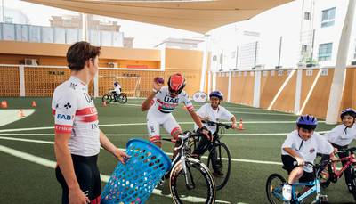 UAE Team Emirates cyclists and schoolchildren participate in a drill.
