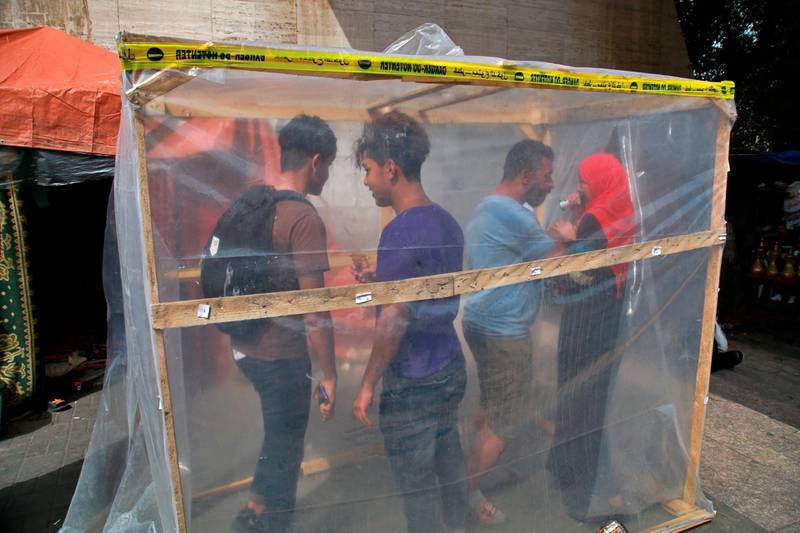 Protesters enter a makeshift disinfecting booth set up by protesters to help protect against the spread of the new coronavirus, during ongoing anti-government protests, in Tahrir Square, Baghdad, Iraq. AP Photo