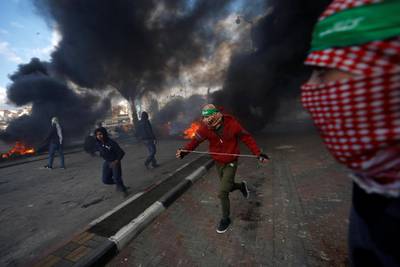 Palestinian protesters run during clashes with Israeli troops near the Jewish settlement of Beit El, close to the West Bank city of Ramallah, on December 7, 2017. Mohamad Torokman / Reuters