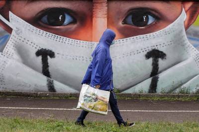 A man walks past by a mural by artist Cosimo Cheone dedicated to nurses of Sacco hospital, in Milan, Italy. AP Photo