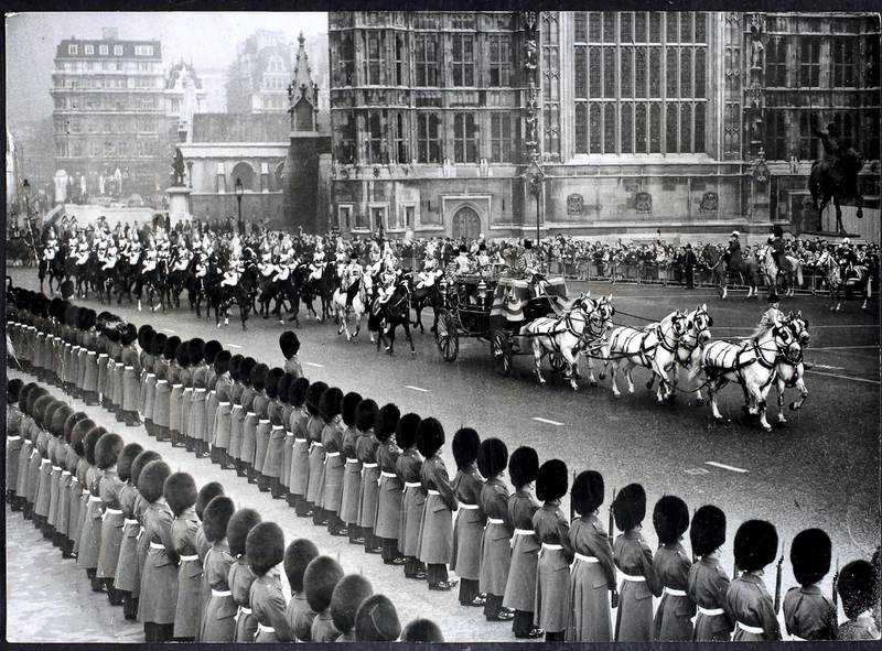 Queen Elizabeth II arrives in the State Coach to perform the State Opening of Parliament, London. The coach, drawn by six Windsor Greys, and accompanied by the Sovereign's escort of Household Cavalry, crosses Standards Green on the approach to the House of Lords, London, England. (Photo by William Vanderson/Fox Photos/Hulton Archive/Getty Images)