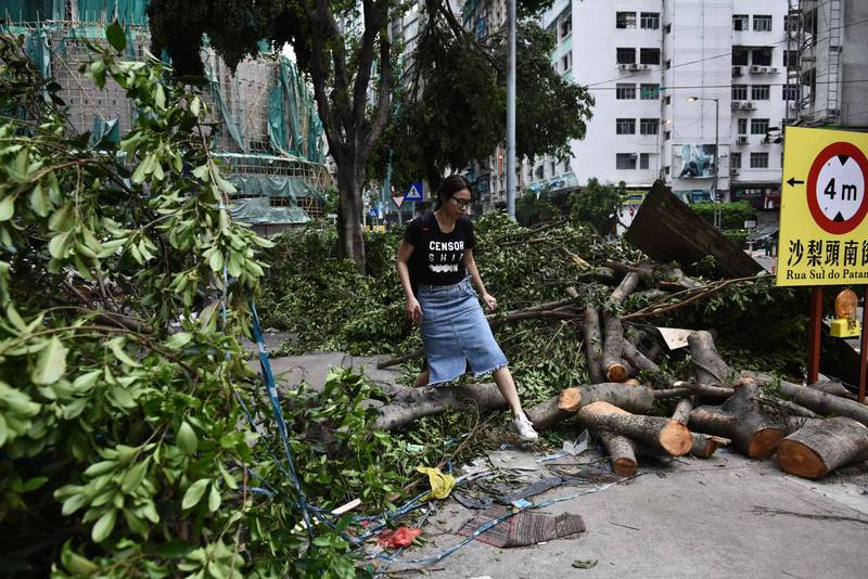 A woman steps over a fallen tree on a pavement in Macau on August 24, 2017. The death toll from Severe Typhoon Hato rose to at least 16 after the storm left a trail of destruction across southern China, blacking out Macau's mega-casinos and battering Hong Kong's skyscrapers. Anthony Wallace / AFP