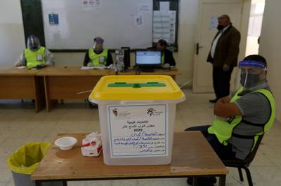 A ballot box is seen as electoral workers sit in a polling station during parliamentary elections in Amman. Reuters