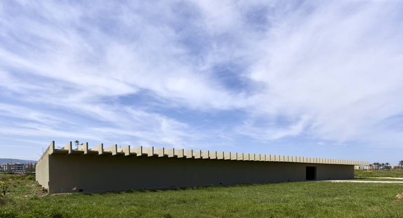 The guest house exposes an elongated profile with its 58-metre main facade, of low height, set on a flat field amid lush green grass. 