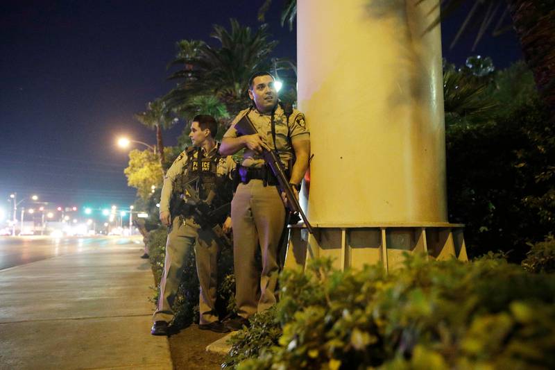 Police officers take cover near the scene of a shooting near the Mandalay Bay resort and casino on the Las Vegas Strip. John Locher / AP Photo